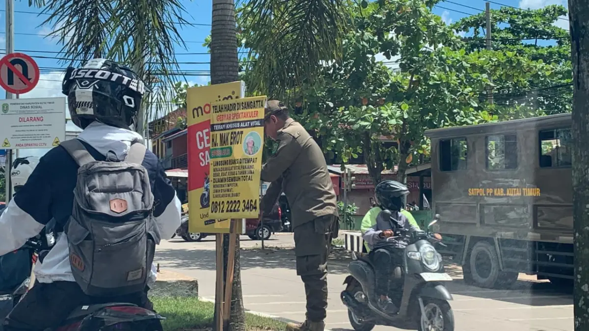 PENERTIBAN: Petugas Satpol PP Kutim menertibkan banner ilegal dan bermuatan vulgar di sejumlah ruas jalan Sangatta, Kamis (21/5). (Ist)