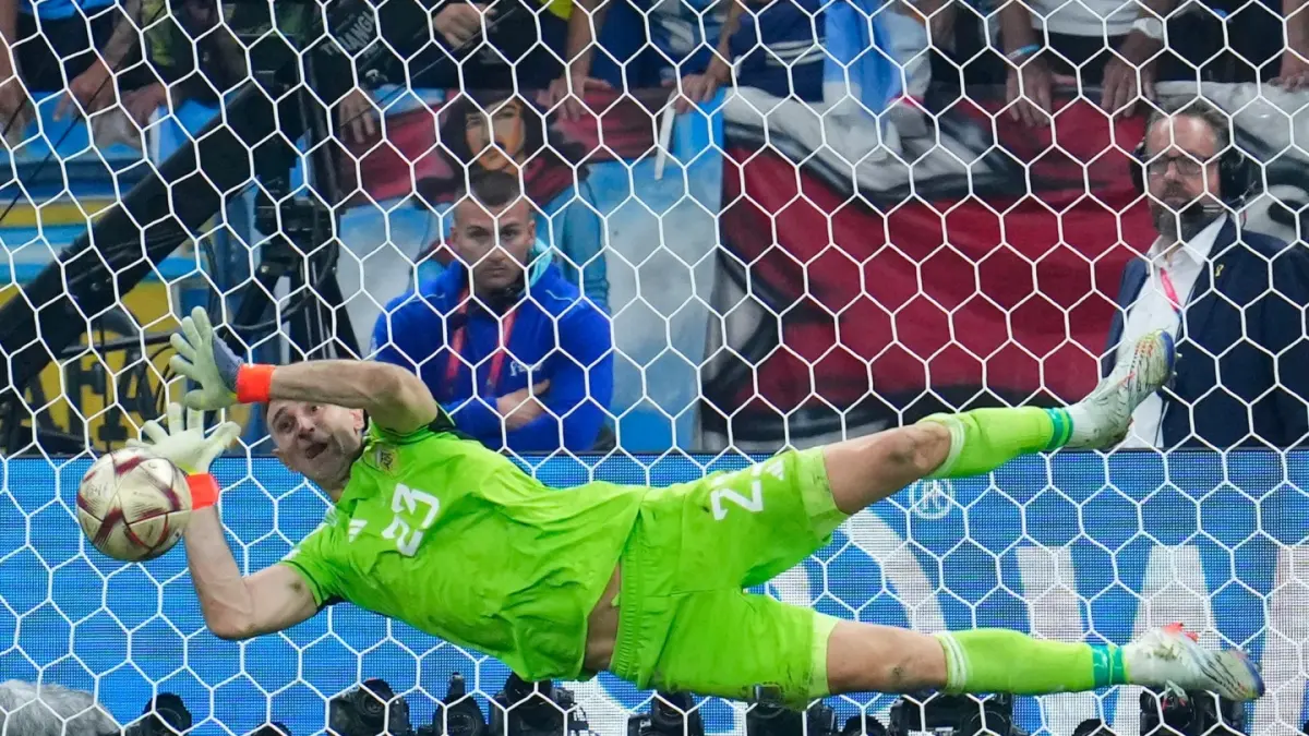 AKSI HEROIK: Kiper Argentina Emiliano Martinez saat menepis tendangan penalti pemain Prancis Kingsley Coman pada final Piala Dunia 2022 di Stadion Lusail, Qatar.(AP)