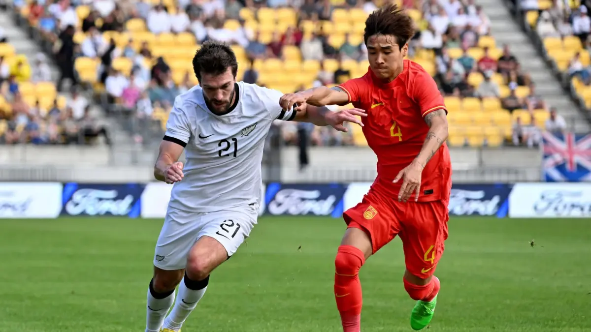 BEREBUT BOLA: Tim Payne (kiri) dan Shihao Wei dari China berebut bola pada pertandingan persahabatan sepak bola internasional, Minggu, 26 Maret 2023.(AP)