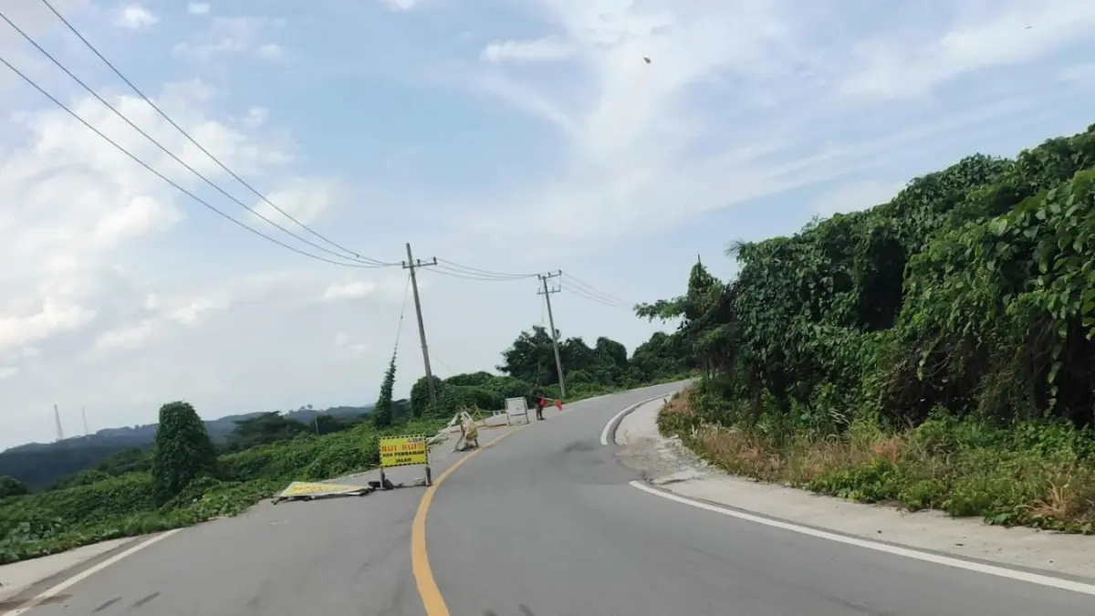 HARUS DITANGANI: Salah satu titik longsoran di Jalan Poros Sangatta–Bengalon menggerus hampir separuh badan jalan. Kondisi tersebut membuat kendaraan harus melintas bergantian. (JUFRIADI/KP)