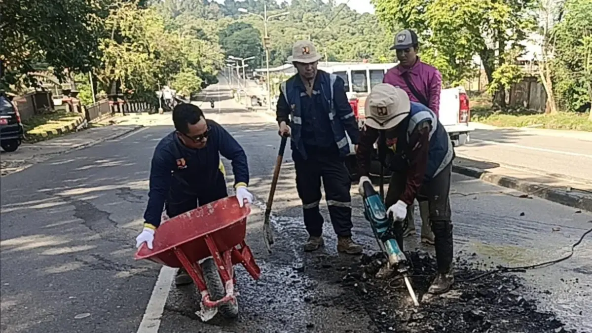TAMBAL: Petugas dari Dinas PUPRK Bontang melakukan penambalan secara sementara agar akses nyaman ketika dilintasi pengendara. ADIEL KUNDHARA/KP