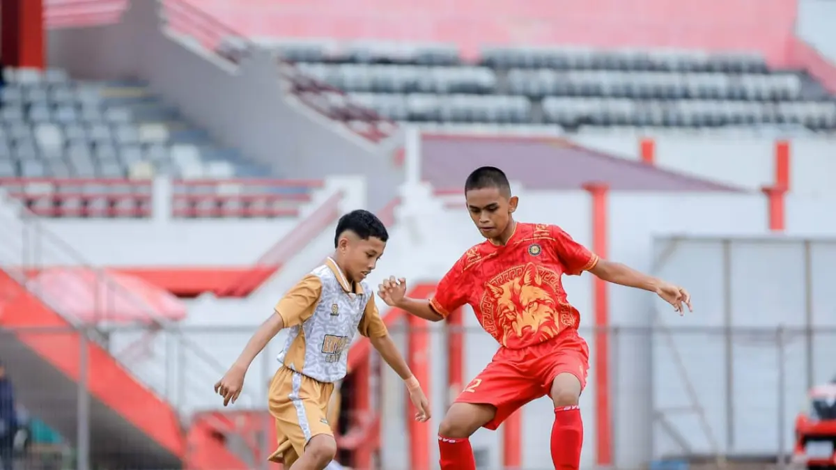 ADANG LAWAN: Pemain GMK, Tegar (jersey putih) berusaha menghentikan pemain SSB Alhidayah saat keduanya bentrok di Piala Soeratin U-13 Regional Kukar. (IST)

&nbsp;