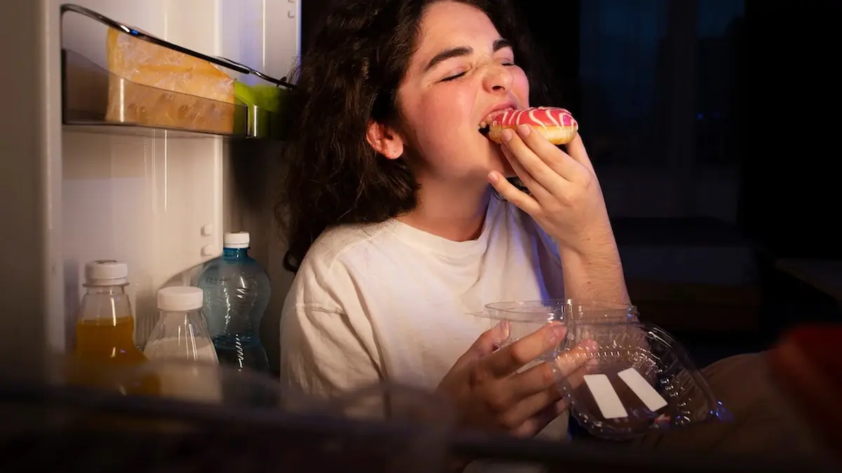 Ilustrasi, seorang wanita memakan donat saat lapar datang di tengah malam. (beautynesia)