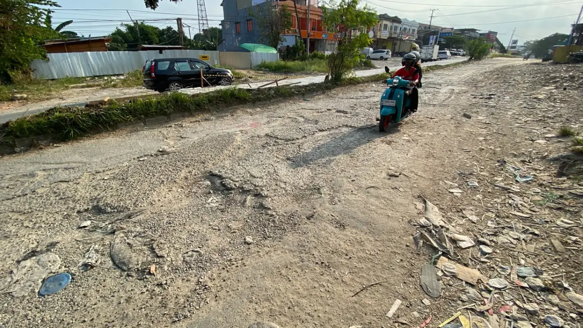 BUTUH ANGGARAN: Kerusakan badan jalan di kawasan Ring Road Samarinda. Tampak aspal terkelupas dan permukaan yang bergelombang. Penanganan komprehensif pada jalur ini terkendala oleh belum terbangunnya drainase utama serta proses pembebasan lahan warga. (RAMA SIHOTANG/KALTIM POST)