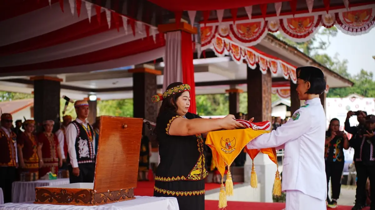 Bupati Mahulu Angela Idang Belawan menyerahkan bendera merah putih kepada pasukan pengibar bendera di Alun-alun Ujoh Bilang, Senin (17/8). (JODY KRISTIANTO/KP)