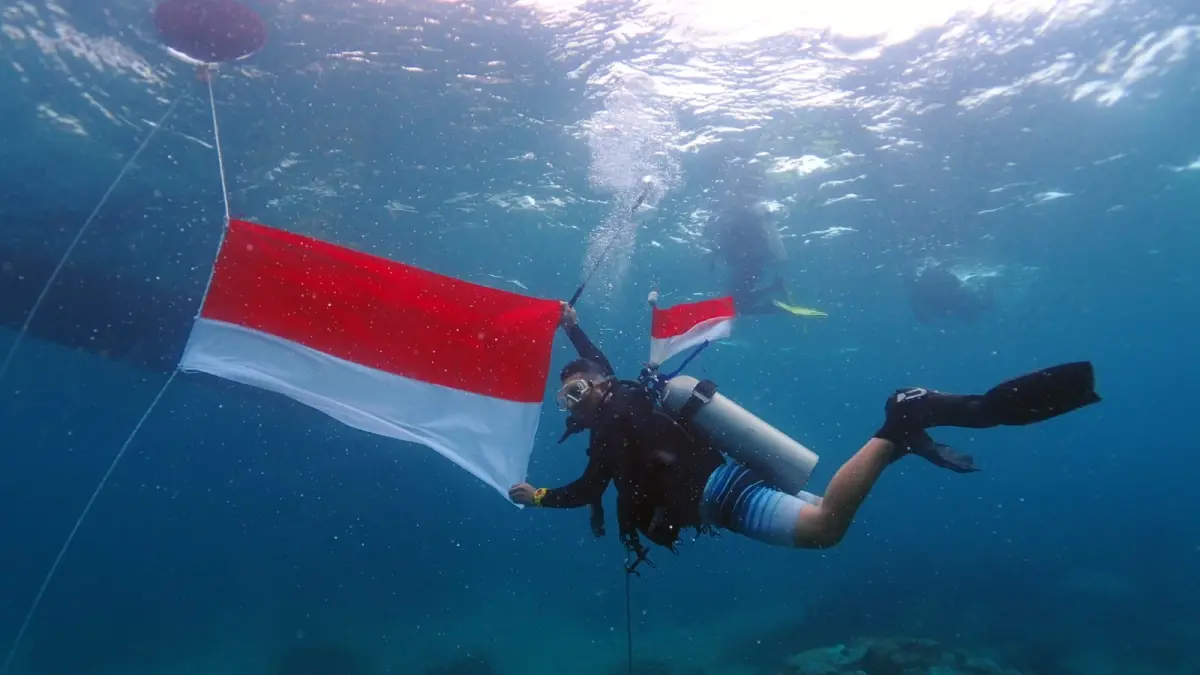 Tim Dinas Pariwisata Kaltim bersama perwakilan jurnalis mengibarkan bendera Merah Putih dan melakukan aksi transplantasi terumbu karang di dasar perairan Pulau Miang, Kecamatan Sangkulirang, Kabupaten Kutai Timur.