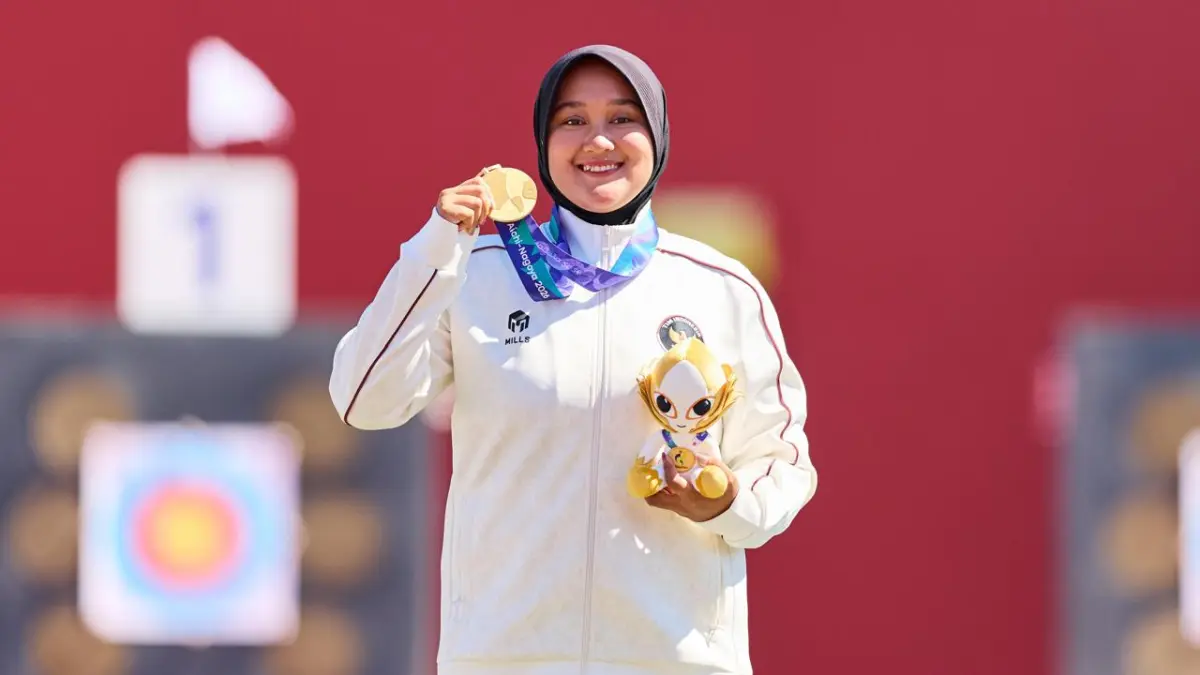 Nurisa Dian Ashrifah alias Hani menunjukkan medali emas usai menjadi juara panahan compound putri Asian Games 2026. (AINAGOC)