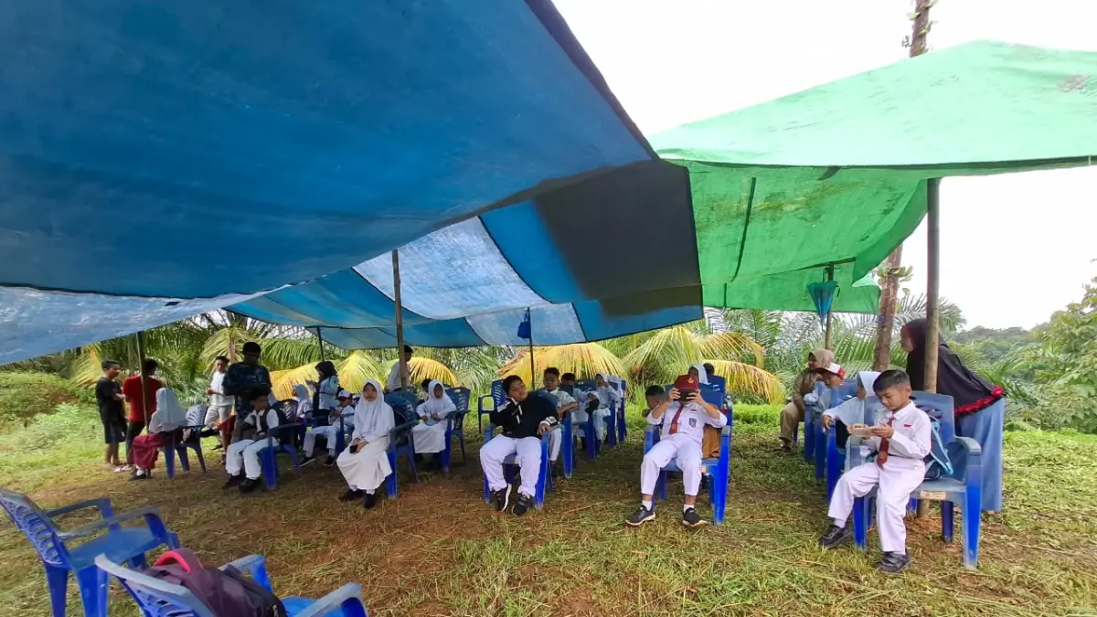 Anak-anak sekolah bersama guru membentang terpal di area perbukitan kawasan Kelurahan Mentawir, Kabupaten Penajam Paser Utara (PPU). Meski berjarak sangat dekat dengan Ibu Kota Nusantara (IKN), wilayah pesisir Teluk Balikpapan ini masih terkendala blank spot parah.