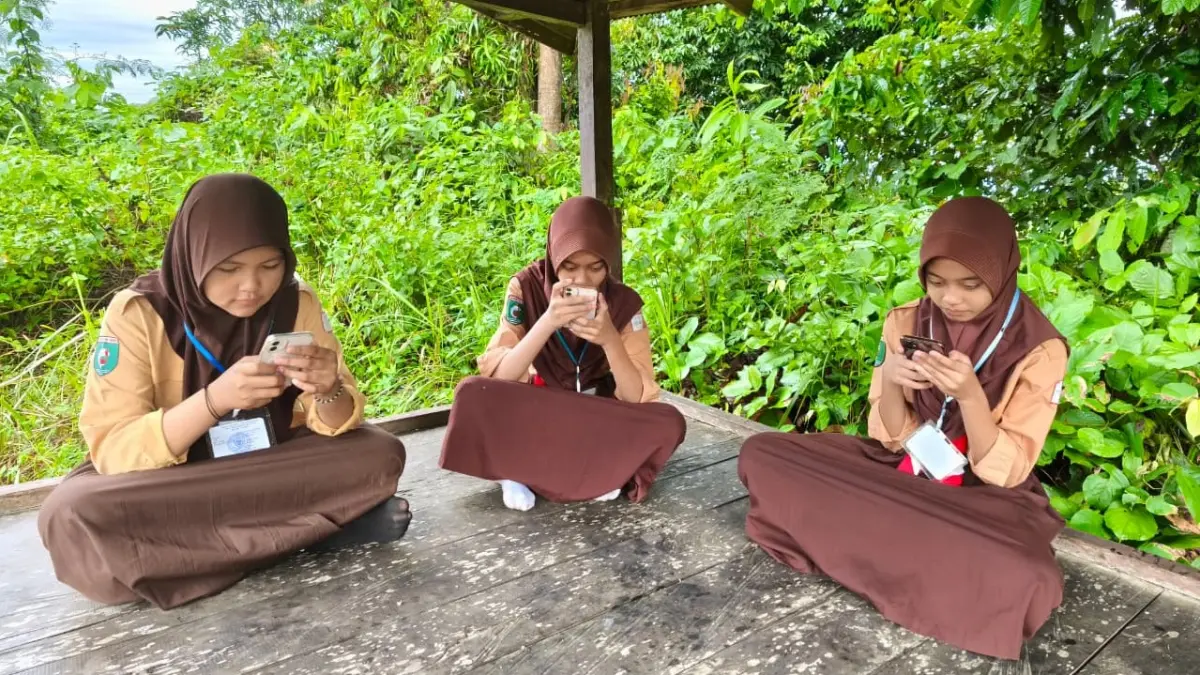 AKSES: Sejumlah siswa SD 007 Sepaku harus berjalan kaki ke area perbukitan demi mendapatkan koneksi internet, sebelum adanya bantuan jaringan selama lebih dari satu dekade. Pemandangan ini kini tak lagi terlihat di lingkungan sekolah seiring terpasangnya akses internet gratis dari program BAKTI Kominfo sejak 2022.