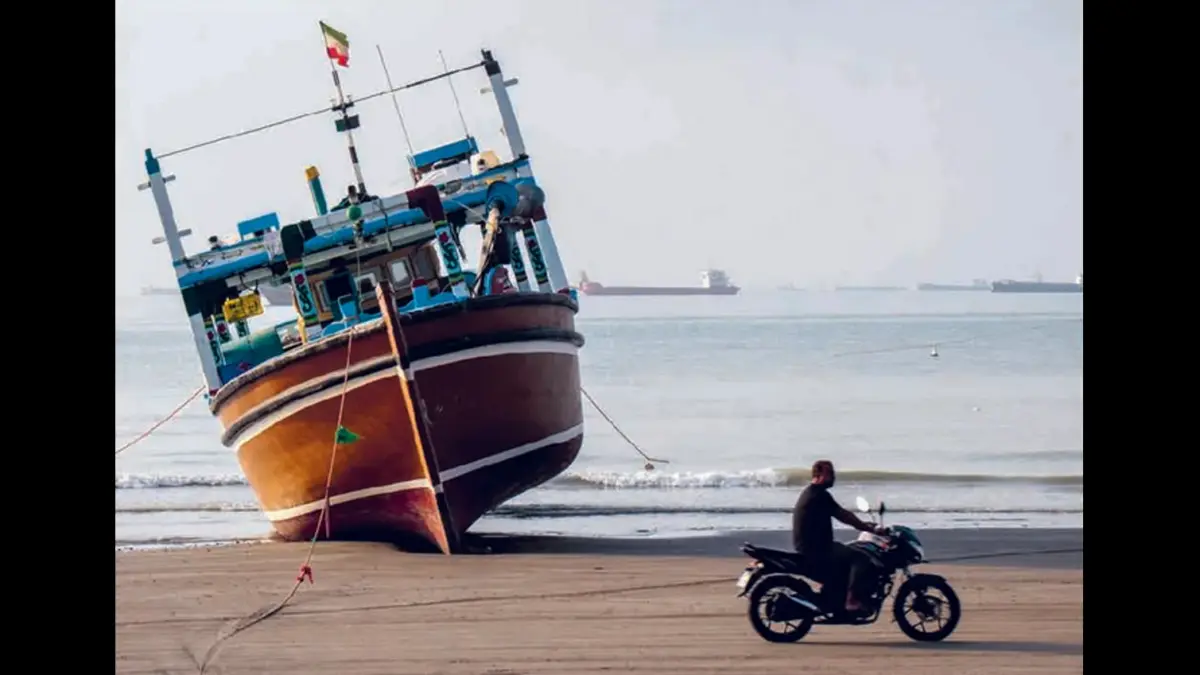 TERDAMPAR: Pengendara motor melewati kapal di Pantai Suru yang berada di sepanjang Selat Hormuz. (AFP)