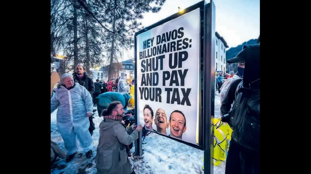 KRITIK PEDAS: Spanduk bergambar potret (dari kiri) Elon Musk, Jeff Bezos, dan Mark Zuckerberg dengan tulisan peringatan untuk membayar pajak di Davos, Swiss.