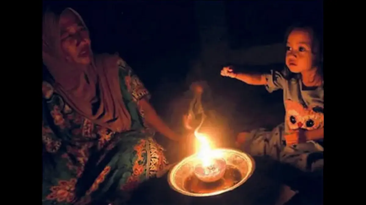 Seorang bocah bermain dengan ibunya di antara temaram lampu tradisional saat pemadaman listrik di Desa Suak Raya, Johan Pahlawan, Aceh Barat, Sabtu (23/5). (SYIFA YULINNAS/ANTARA FOTO)