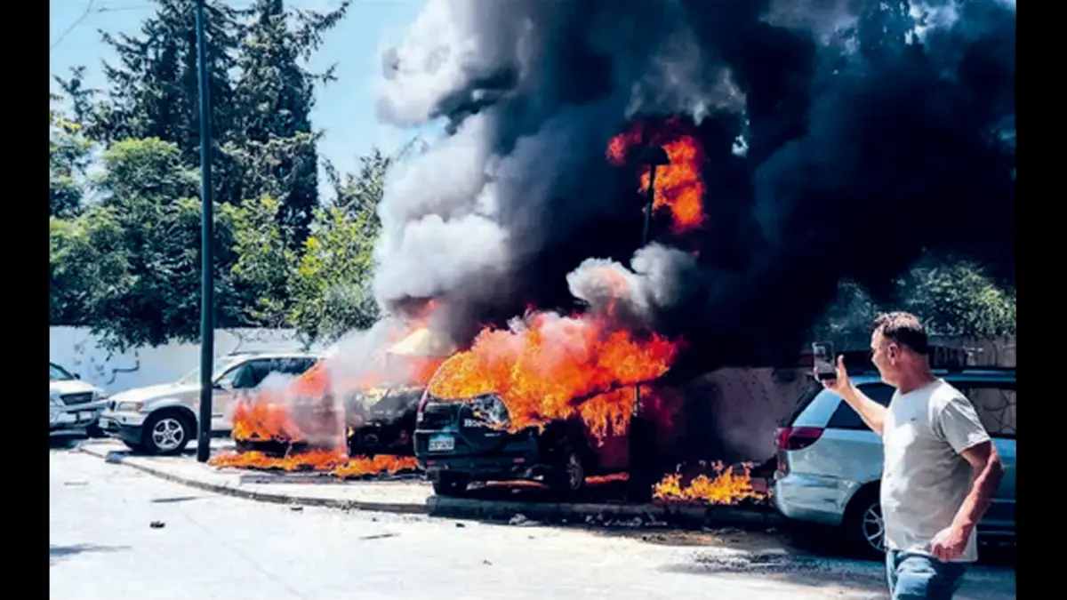 KAWASAN KONFLIK: Seorang pria merekam mobil yang terbakar setelah serangan udara Israel di Lebanon, Rabu (10/6). (AFP)