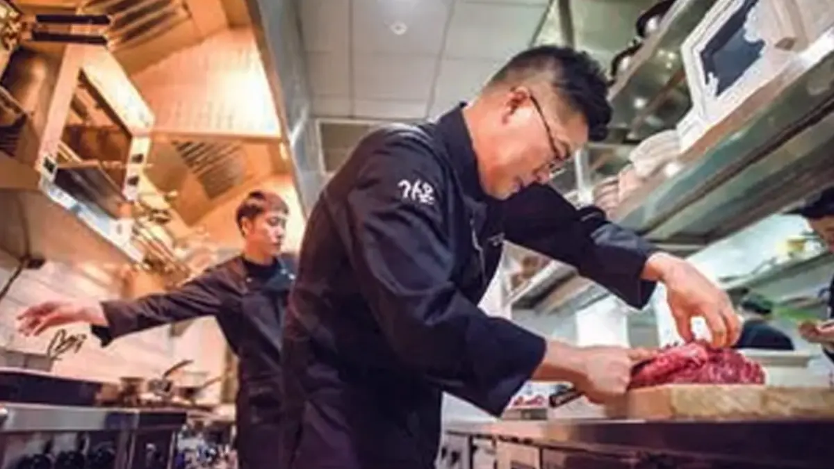 LAYANI PELANGGAN: Koki restoran berbintang Michelin sedang menyajikan makanan di dapur di Seoul, Korea Selatan. (Foto: ED JONES/AFP)