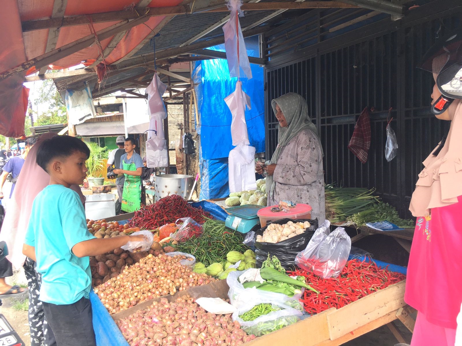 Salah seorang pedagang sembako di Pasar Pagi Lubuklintah saat melayani pembeli di lapaknya, Jumat (5/3). (SILVINA/PADEK)