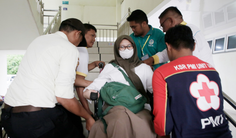 Panitia UTBK UNP dengan penuh kepedulian membantu Nadira naik ke lantai 2 ruangan ujiannya. (Foto: Humas UNP)