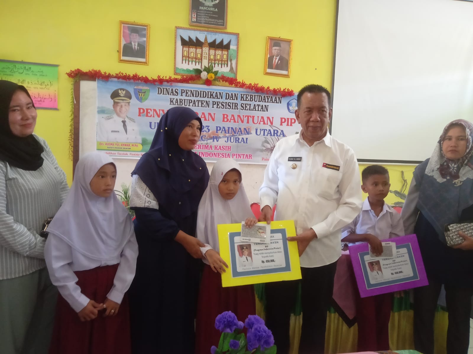 Bupati Pessel, Rusma Yul Anwar, saat menyerahkan bantuan PIP secara simbolis kepada siswa penerima bantuan di SDN 23 Painan Utara dengan didampingi orang tua. (dok yon)