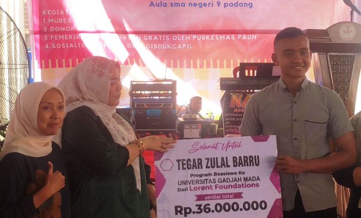 Ketua Yayasan Padusi Peduli Nagari, Sovia Lorent, menyerahkan bantuan beasiswa kepada Tegar Zulal Barru, siswa SMAN 9 yang diterima di UGM dalam rangkaian acara Reuni Akbar dan Mubes II SMANSE.