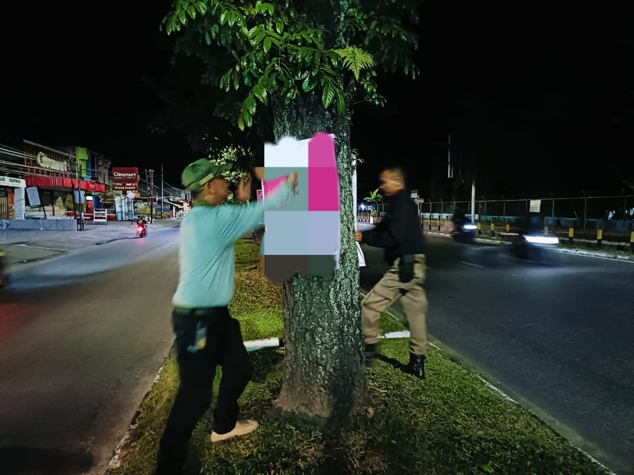 Personel Satpol PP Padang membongkar baliho yang terpasang di Jalan Hamka, Minggu (7/7) dini hari. (SATPOL PP PADANG)