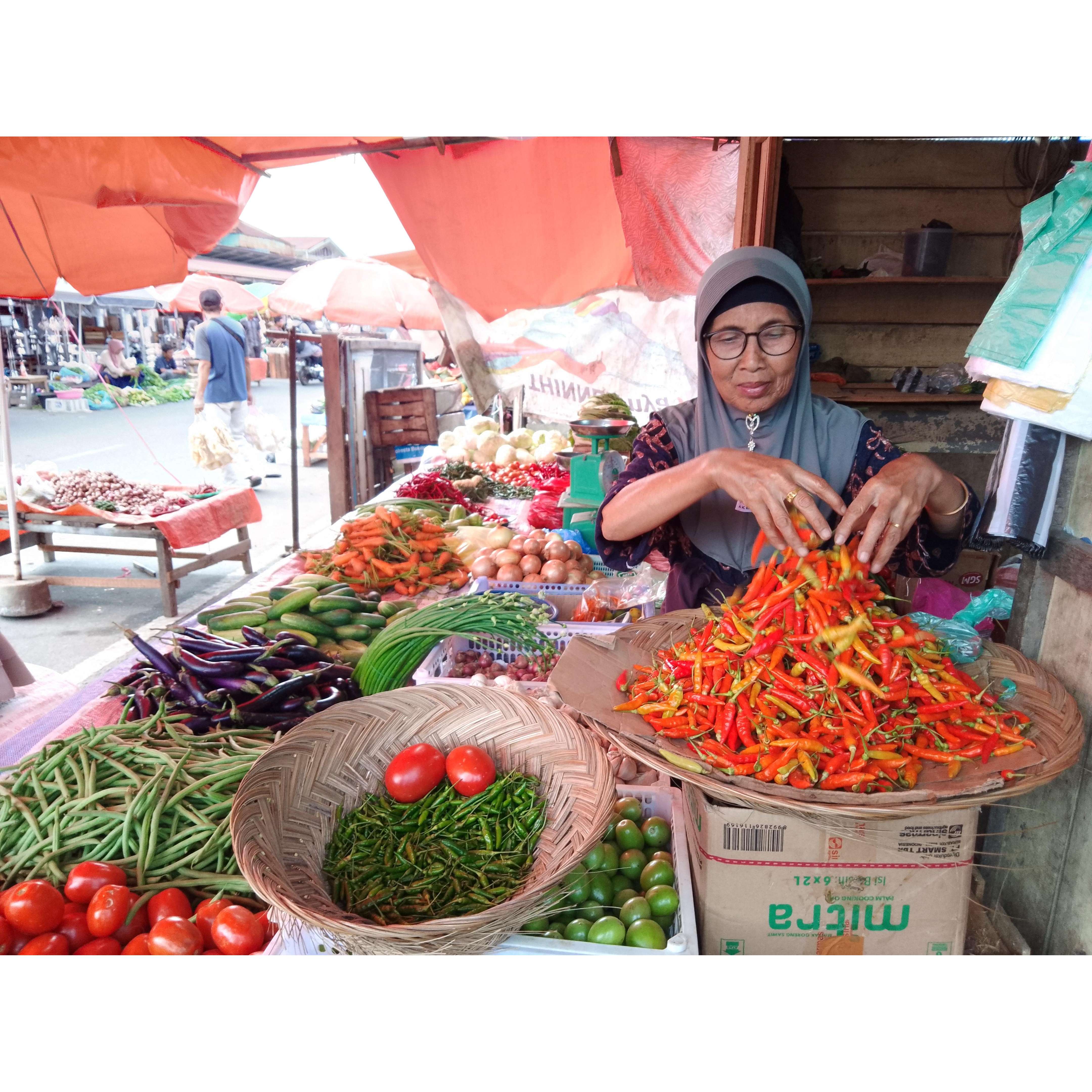 MULAI MELANDAI: Wirniati, pedagang sembako di Pasar Bawah Bukittinggi menata dagangannya sembari menunggu pembeli, Selasa (16/7).(RIAN AFDOL/PADANG EKSPRES)