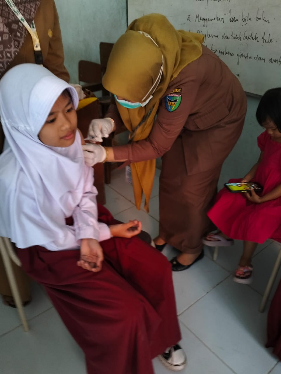 Bidan desa UPT Puskesmas Tapan, saat melakukan imunisasi BIAS terhadap anak di SDN 03 Malepang Tapan. (dok Dinkes)