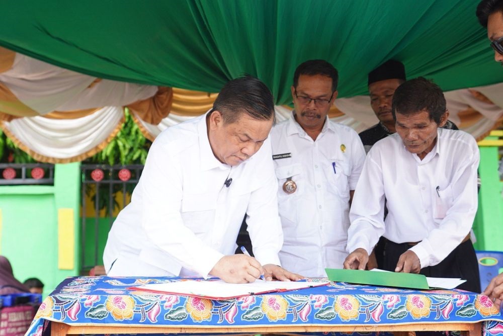 PENYERAHAN: Penandatanganan naskah dan sertifikat hibah oleh Sekprov Riau, SF Hariyanto dan Penghulu Balam Jaya, Mangapul Nababan, Rabu (11/9). (MEDIA CENTER RIAU)