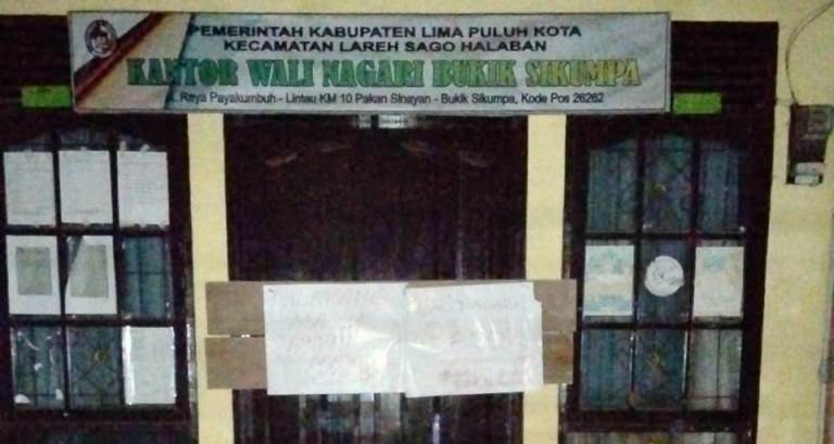 Terlihat Kantor Wali Nagari Bukik Sikumpua, Kecamatan Lareh Sago Halaban, terpasang garis pembatas dan papan di pintu depan, Kamis (10/10) malam.