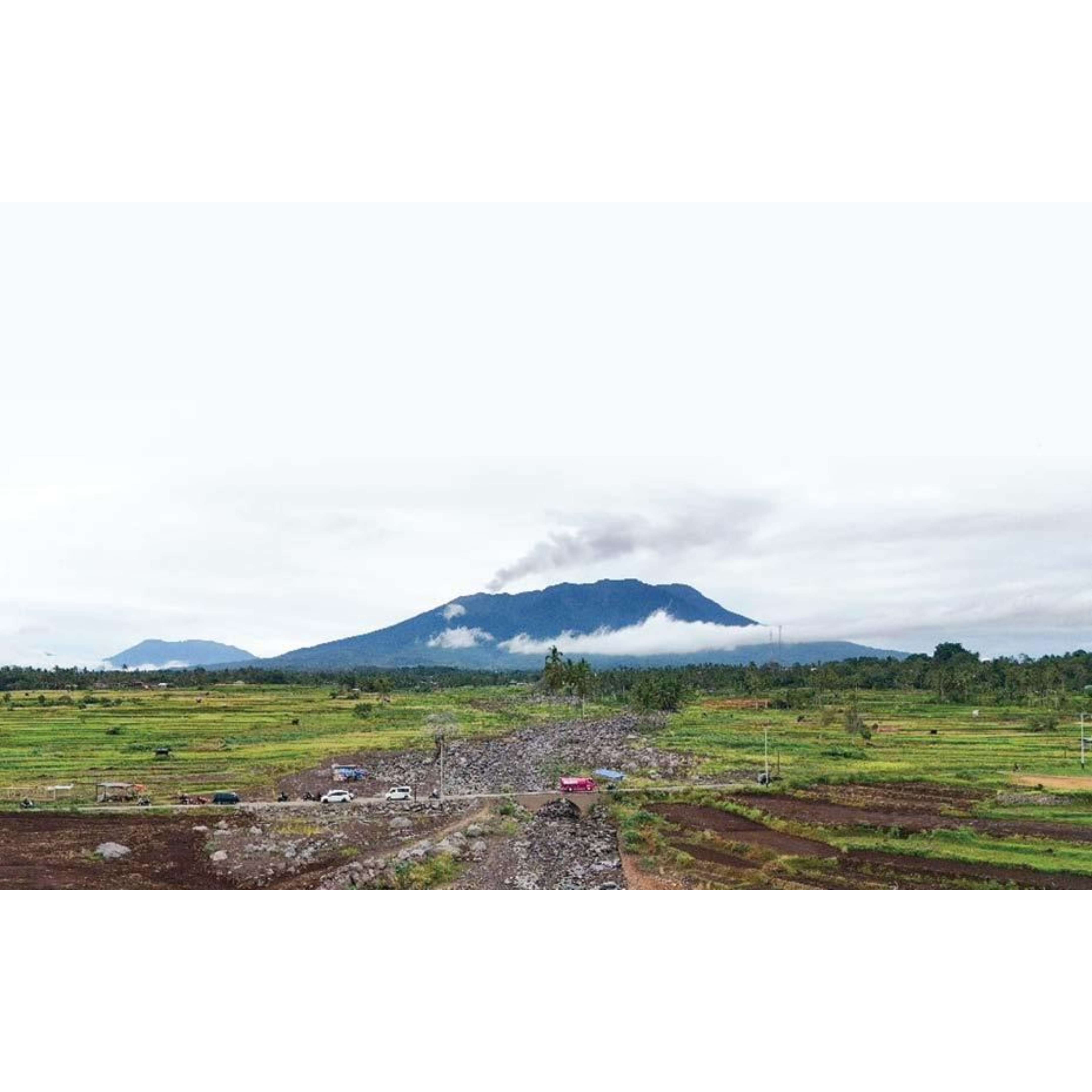 HARUS JADI PERHATIAN: Sejumlah kendaraan melintasi kawasan bekas galodo di Rambatan, Kabupaten Tanahdatar, Rabu (6/11), dengan pemadangan erupsi Gunung Marapi. (FANANDA ARIANAGA UNTUK PADEK)