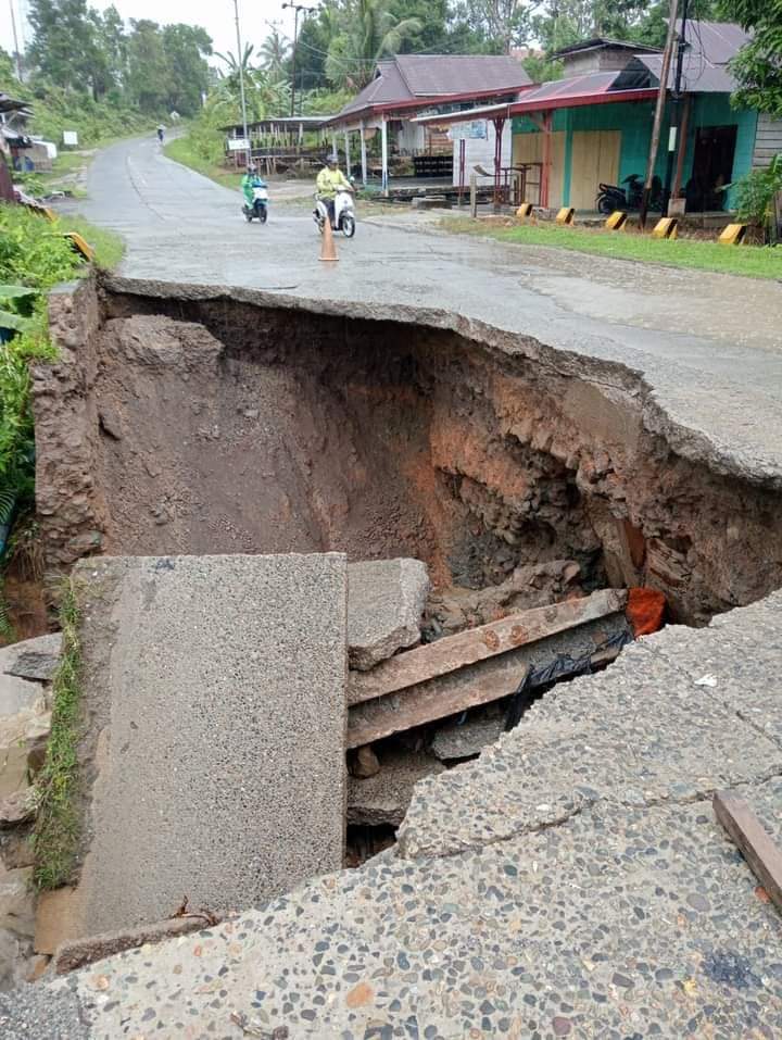 HARUS SEGERA DITANGANI: Kendaraan melintas di kawasan jalan nasional di Jalan Raya Tuapejat, Mentawai, kilometer 8 yang amblas dengan diameter sekitar 4 meter x 4 meter. (ARIF/PADEK)