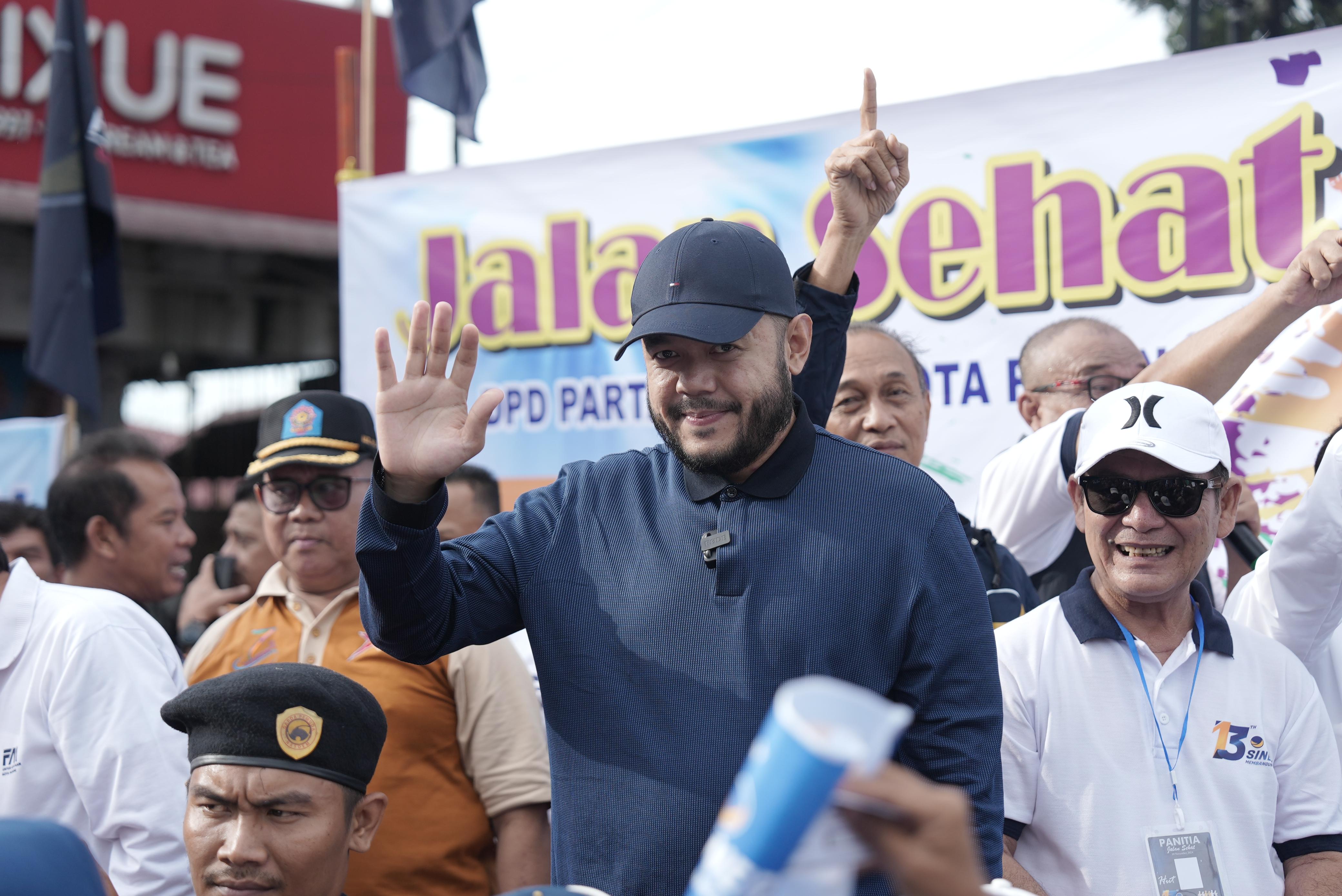 DISAMBUT ANTUSIAS: Cawako dan cawawako Padang nomor urut 1, Fadly Amran-Maigus Nasir di tengah-tengah peserta jalan sehat untuk  memperingati HUT Nasdem ke-13 di Padang, kemarin. (TIM FADLY AMRAN)