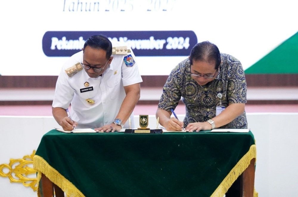 KOMITMEN: Pj Gubernur Riau Rahman Hadi dan Deputi Direksi Wilayah II BPJS Kesehatan, Eddy Sulistijantoe Hadie menandatangani nota kesepahaman  2025-2027, Rabu(20/11). (DOK MEDIA CENTER RIAU)