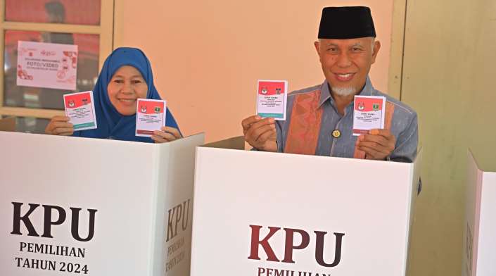Mahyeldi dan Harneli Bahar memperlihatkan surat suara saat menyalurkan hak pilih di TPS 005 Kompleks Kampus STISIP Imam Bonjol Jati Baru, Kota Padang.