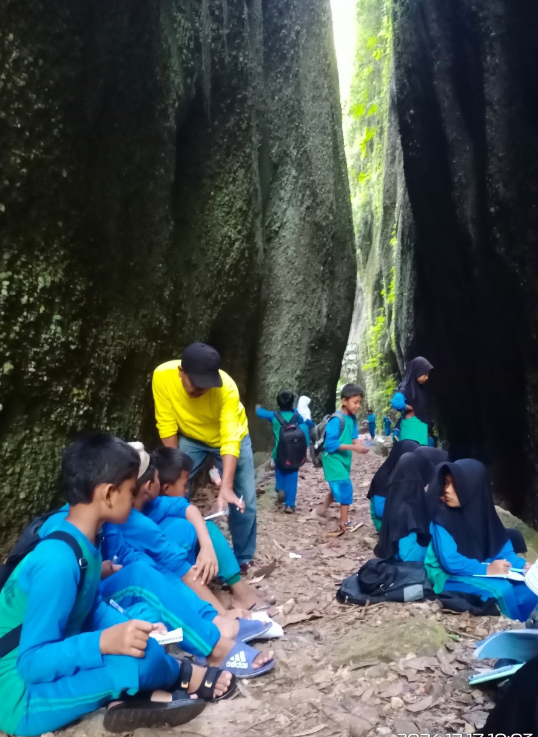 Murid SDN 12 Nagari Padang Laweh Sijunjung, melakukan kegiatan trekking dan mencatat kondisi geologi di sepanjang perjalanan menuju Geosite Konglomerat Brani Ngalau Batauik. (Foto: Ridwan)