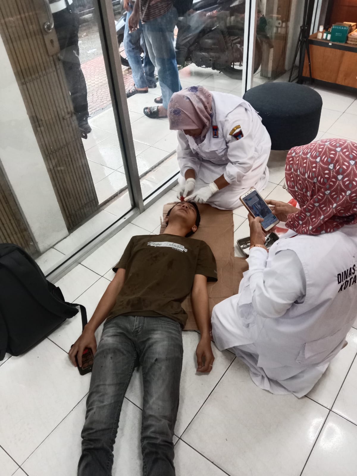 Petugas kesehatan sedang memberikan penanganan medis kepada pejalan kaki yang menjadi korban pelemparan oleh ODGJ di Jalan Hamka, Padang, Selasa (24/12/2024).