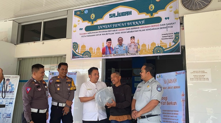 APRESIASI: Kepala UPTD PPD Kota Pariaman, Nanda Edya Putra didampingi Satlantas Polres Kota Pariaman dan pihak PT Jasa Raharja memberikan doorprise kepada salah seorang warga.(PPD KOTA PARIAMAN)