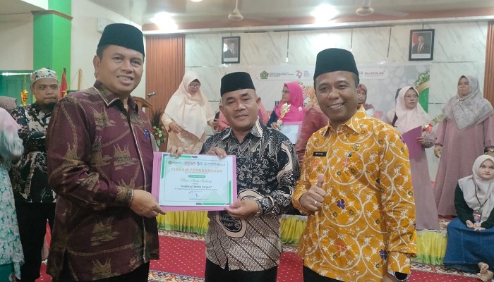 REWARD: Kakan Kemenag Kota Padang, Edy Oktafiandi menyerahkan penghargaan kepada Wakahumas MTsN 1 Kota Padang, Dafril disaksikan Kepala MTsN 1 Padang, Isrizal.(TIM LAMAN GURU)