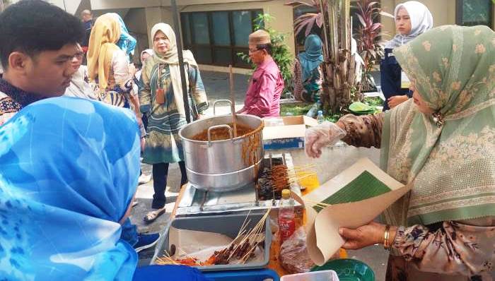 Seorang pelaku usaha mikro, jual sate, terlihat sedang melayani pembeli.