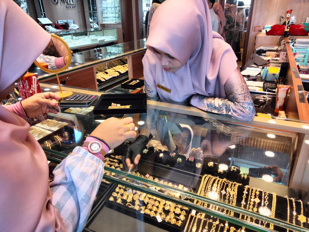Salah seorang karyawan toko emas di Pasar Raya Padang sedang melayani pelanggan.