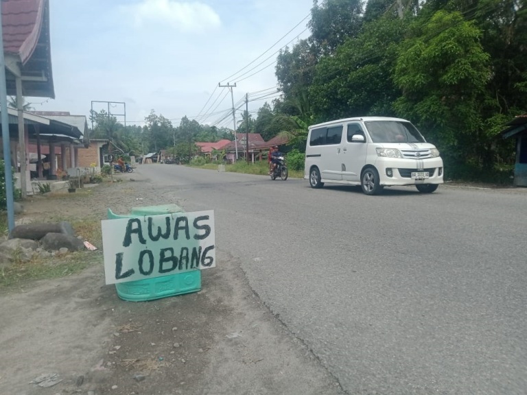 MEMBAHAYAKAN: Masyarakat berharap agar lubang jalan di Kotomambang segera diperbaiki. Sebab, jalan lintas provinsi belakangan makin ramai dilalui kendaraan.(ARIS/PADEK)