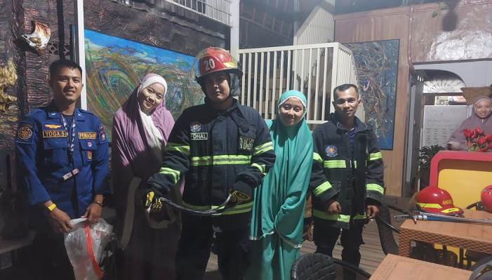 Tim Dinas Damkar Kota Padang mengevakuasi ular kobra yang keluar dari lubang kloset rumah kos di Parupuktabing, Kota Padang, Rabu (12/3/2025). (Dinas Damkar Padang)