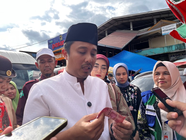 WASPADA UPAL: Wagub Sumbar Vasco Ruseimy saat memegang uang palsu yang bikin heboh pedagang dan pengunjung Pasar Bandarbuat, Padang, Kamis (13/3).(SHYNTIA/PADEK)