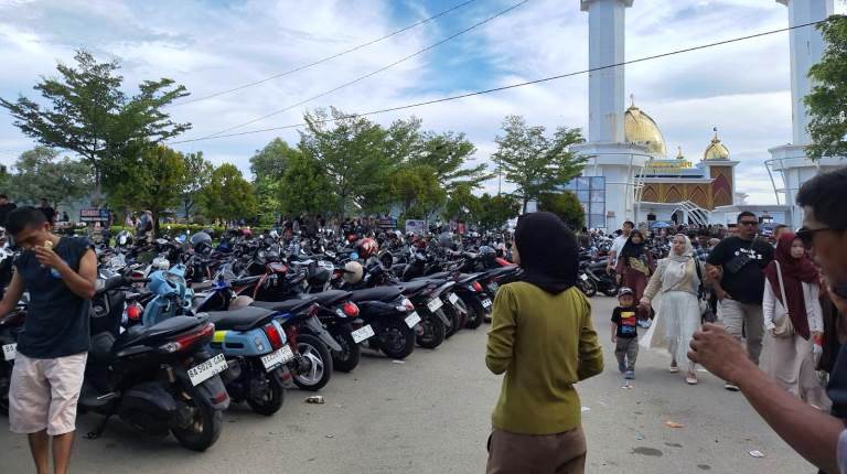 Pengunjung memadati Pantai Carocok Painan dengan latar Masjid Terapung Samudra Ilaihi dan lokasi parkir kendaraan roda dua. (Foto: Brian/Kominfo)