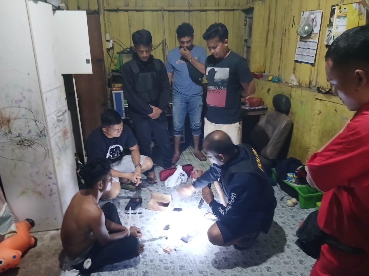 TIDAK BERKUTIK: Petugas Satresnarkoba Polres Dharmasraya saat mengamankan barang bukti dari tangan tersangka IGR, berupa sabu, timbangan digital, alat hisap, serta uang tunai.(DOK.POLRES DHARMASRAYA)