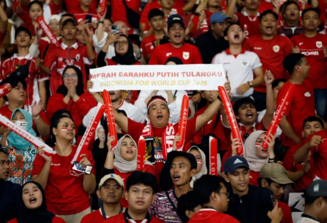 Seorang suporter Indonesia mengangkat spanduk dukungan untuk Timnas Indonesia yang tengah berjuang lolos ke Piala Dunia 2026. (Foto: Ajeng Dinar Ulfiana/Reuters)