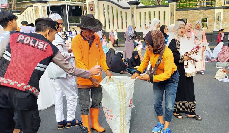 Usai salat id, petugas bergerak membersihkan sisa koran bekas yang digunakan sebagai alas sajadah.