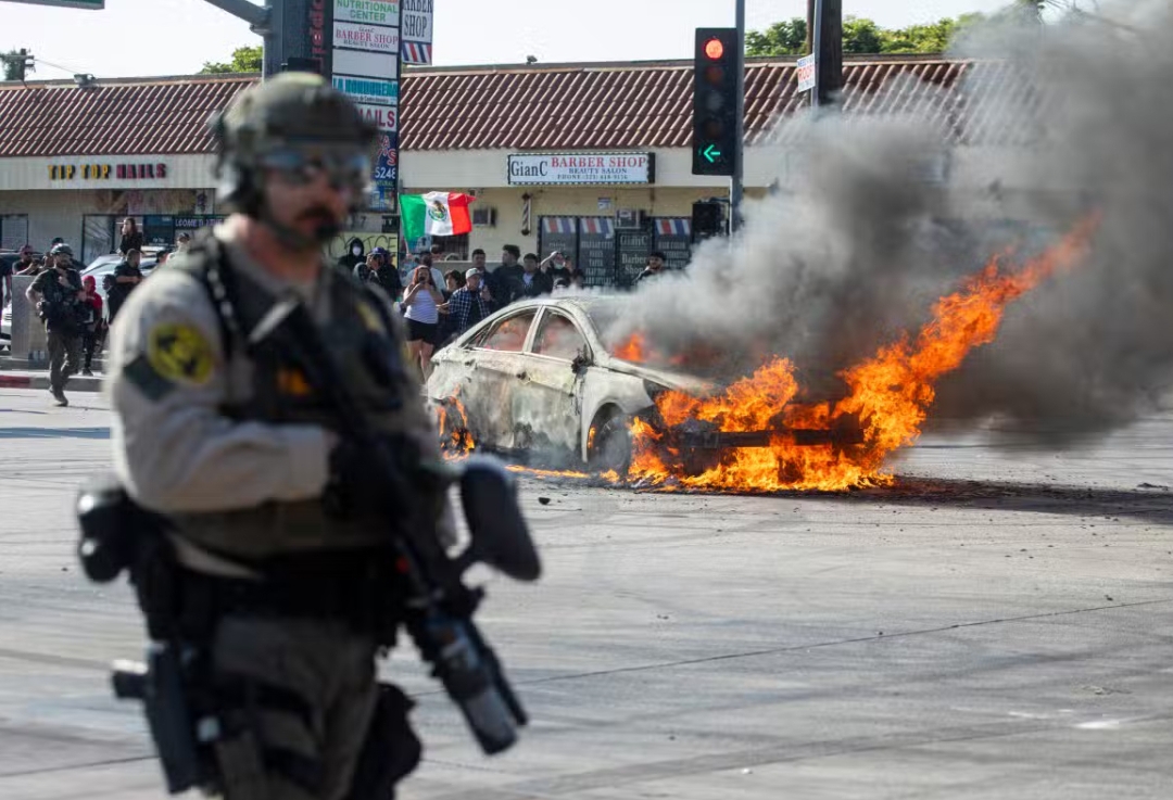 Sebuah mobil terbakar saat aksi protes terhadap razia imigrasi federal, di lingkungan Compton, Los Angeles, California pada 7 Juni 2025. (Foto: AFP)