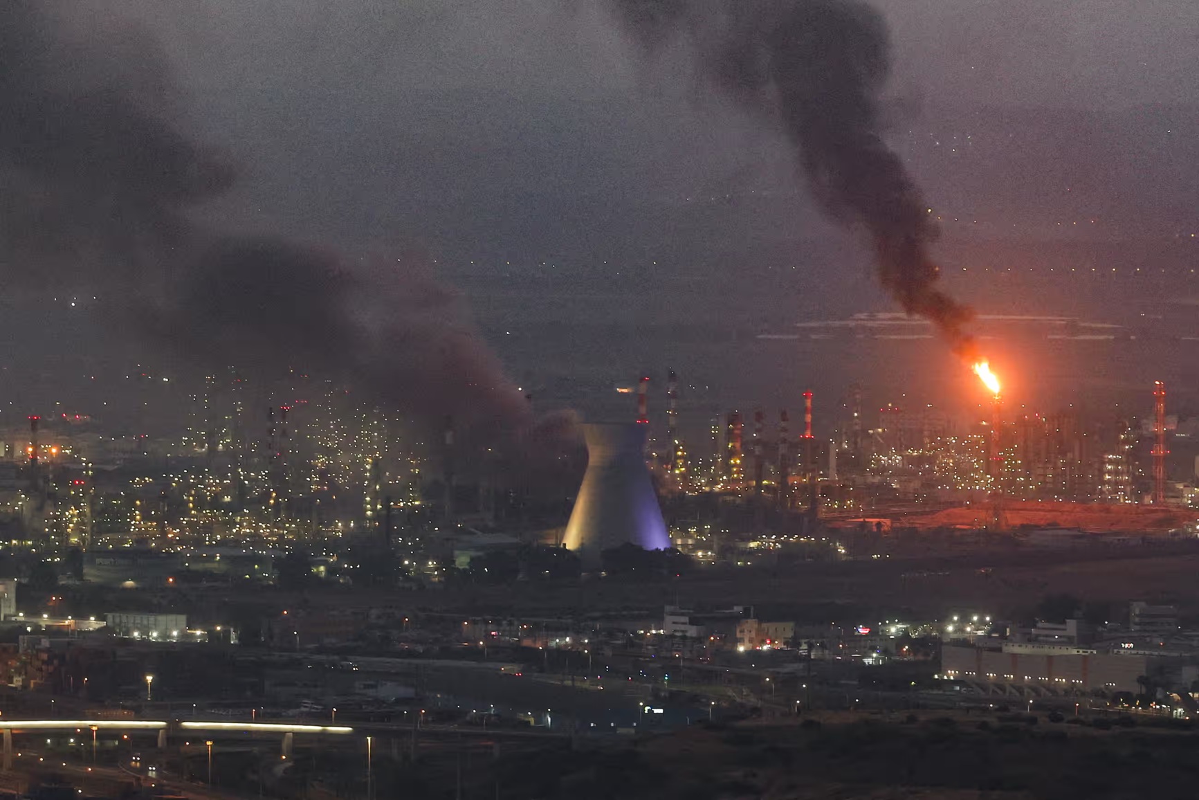 EKSKALASI KONFLIK: Asap mengepul di Haifa, Israel, menyusul rentetan serangan misil Iran kemarin (16/6). Kedua negara bergantian meluncurkan serangan.(AHMAD GHARABLI/AFP VIA THE GUARDIAN)