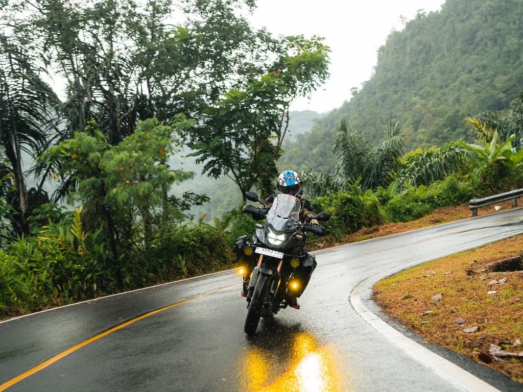 Seorang pengendara motor sedang melewati jalanan menurun dan licin.