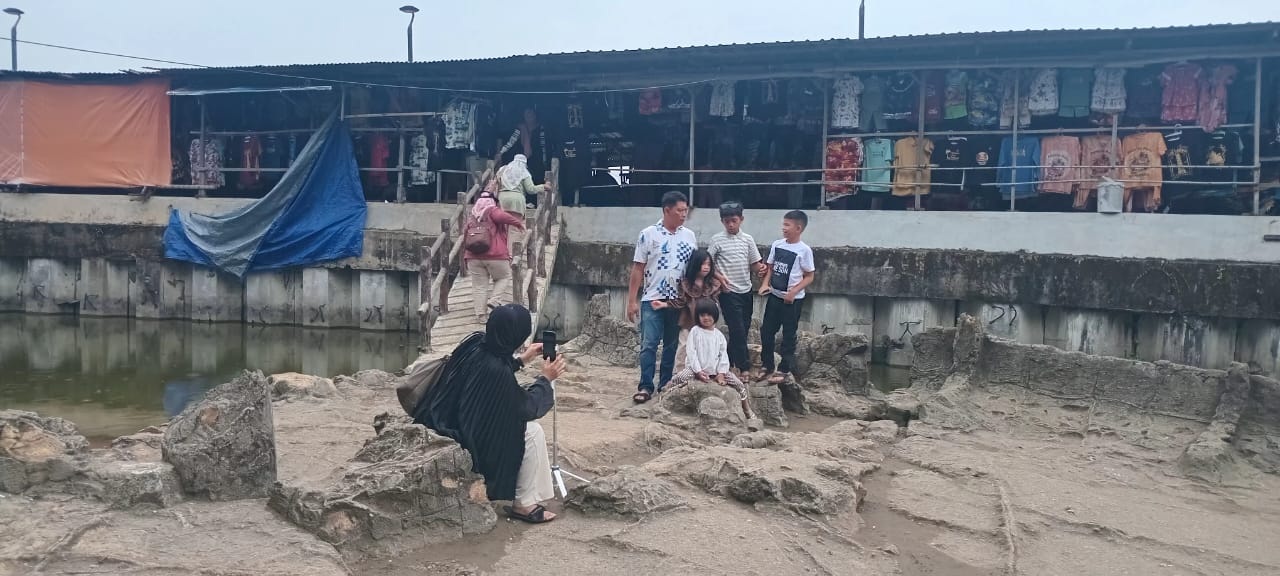 Wisatawan mengabadikan momen di Batu Malin Kundang, spot favorit di Pantai Airmanis.