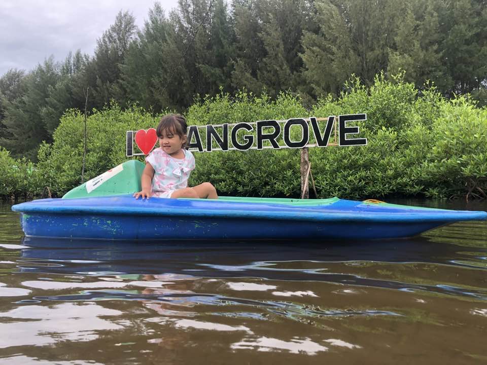 Seorang anak sedang tracking mangrove dengan perahu kano.